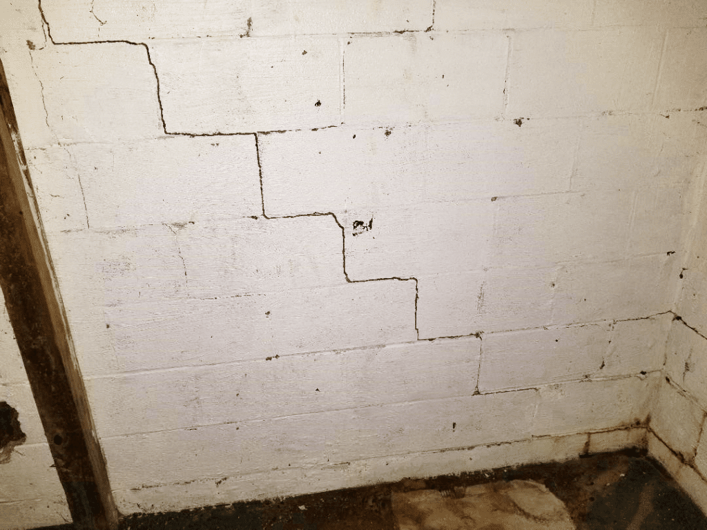 Foundation wall with stair-step crack, indicating potential structural issues in basement, relevant to foundation repair and waterproofing services.