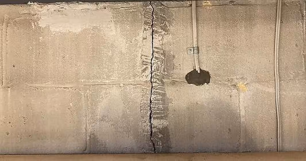 Vertical foundation crack in a basement wall showing signs of structural movement and water intrusion