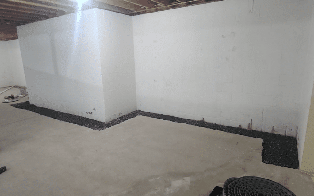 Basement interior with gravel along the walls, illustrating preparation for waterproofing methods to prevent moisture intrusion and structural damage.