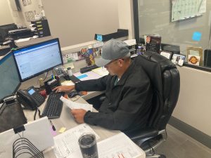 Person working at a desk with a computer and paperwork, illustrating office environment related to basement waterproofing services.