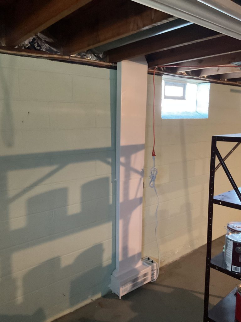 Basement interior featuring a painted wall, heating unit, and window, illustrating a waterproofing project environment.