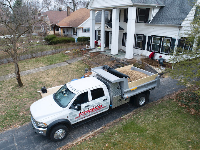Ohio State Waterproofing truck parked in front of a residential home, ready for basement waterproofing services, with workers preparing the site.